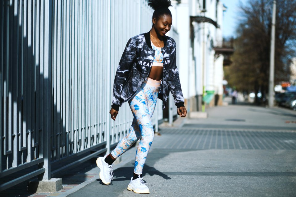 Woman Wearing Black Jacket And White Pants Standing On Grey Concrete Pavement