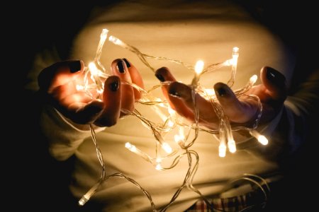 Closeup Photo Of Person Wearing White Long-sleeved Shirt Holding Turned On String Lights photo