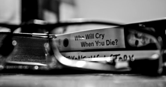 Grayscale Photography View Through Eyeglasses Who Will Cry When You Die Labeled Book photo