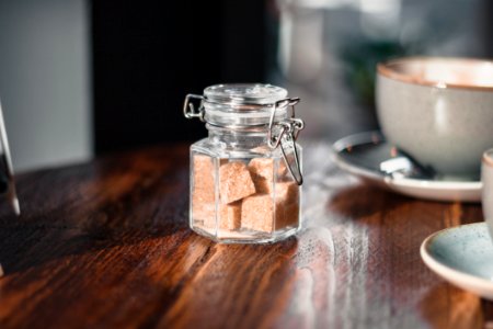 Clear Condiment Shaker With Brown Sugar Cubes Near Gray Teacup photo