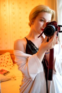 Woman Wearing Black Lace Floral Spaghetti Strap Dress Holding Black And Red Samsung Bridge Camera In Room photo