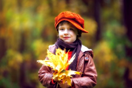 Boy Wearing Brown Leather Jacket Holding Yellow Leaves photo