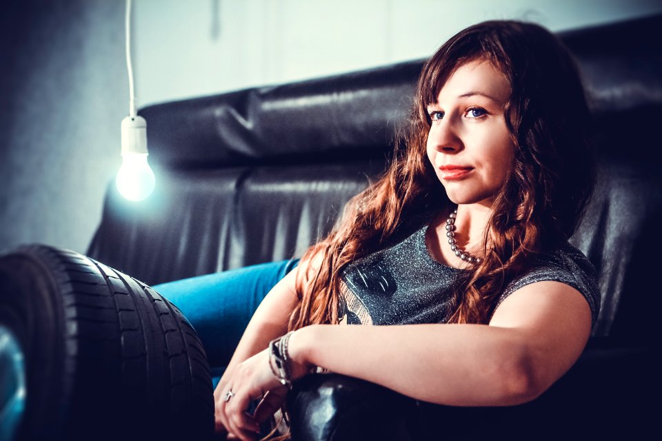 Woman In Gray Shirt Lying On Black Seat Sofa With Bulb Beside