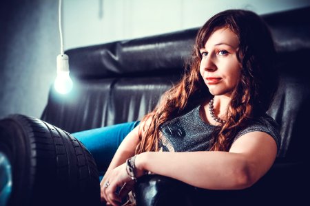 Woman In Gray Shirt Lying On Black Seat Sofa With Bulb Beside