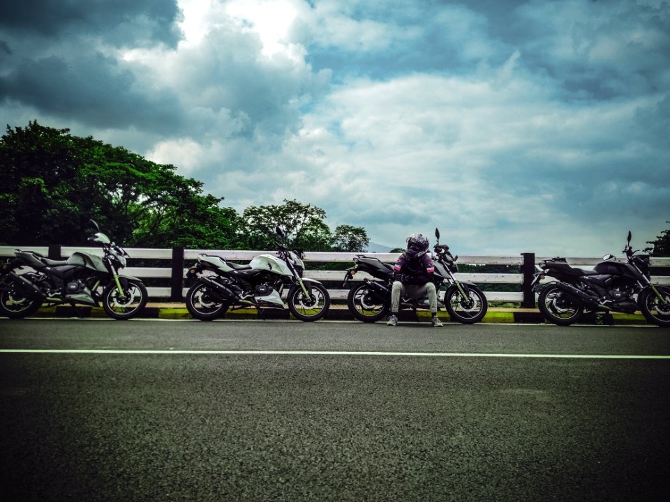 Man On Asphalt Road Sitting Beside Sports Bike Under White Clouds Blue Skies Daytime
