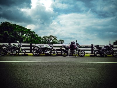 Man On Asphalt Road Sitting Beside Sports Bike Under White Clouds Blue Skies Daytime