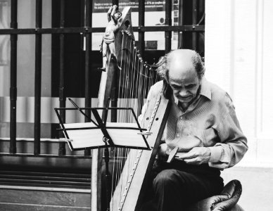 Greyscale Photo Of Man Holding Harp photo