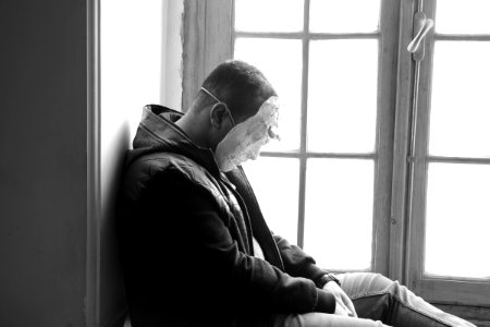 Man Wearing Mask Sitting Near Window Panel photo