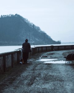 Man Wearing Brown Coat Near A Body Of Water With Fishing Rods At Daytime photo