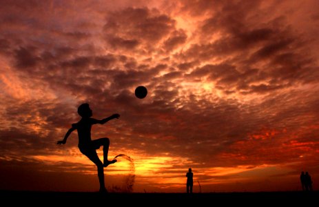 Silhouette Of A Boy Playing Ball During Sunset photo