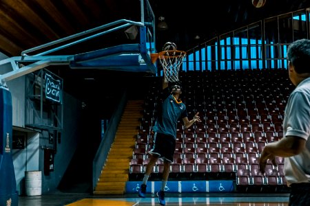 Man In Blue Shirt Trying To Dunk In Basketball Ring photo