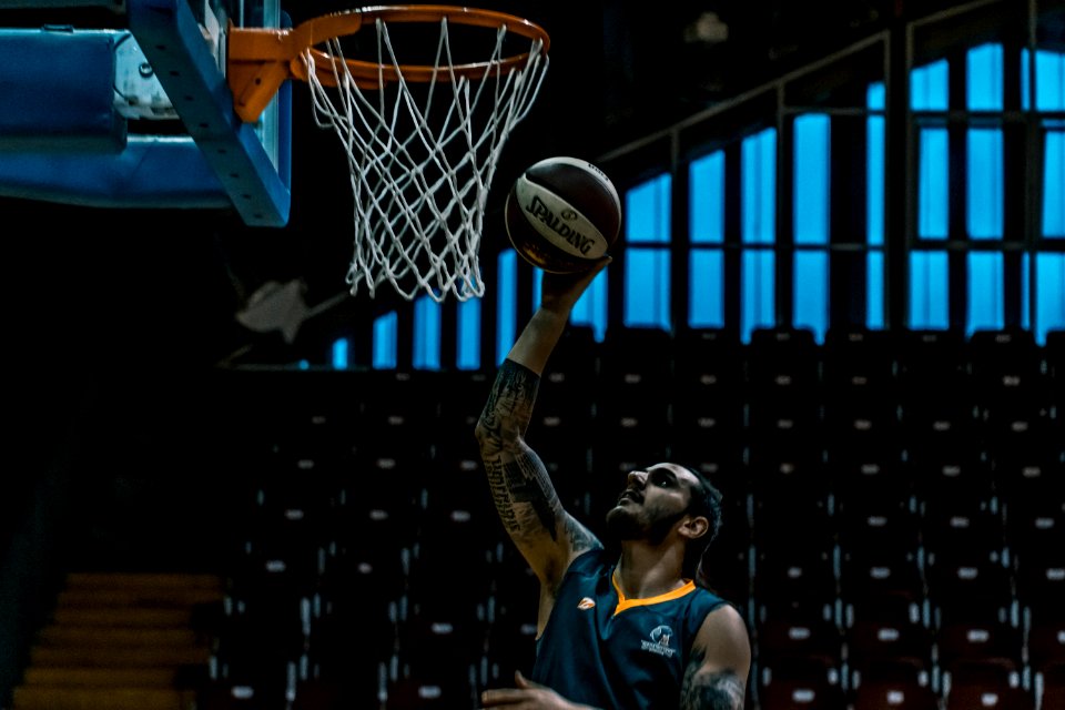 Man Holding White And Black Spalding Basketball Near Brown And White Basketball Hoop