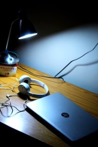 Gray Hp Laptop And White Corded Headphones On Brown Wooden Table photo