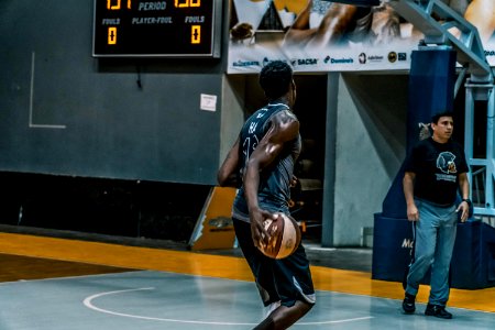 Man Holding Basketball On Blue Floor photo