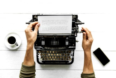 Person Holding White Paper And Typewriter photo