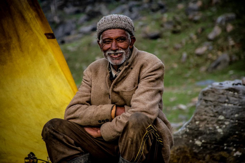 Smiling Man Wearing Gray Knit Cap Sitting Near Gray Rock photo