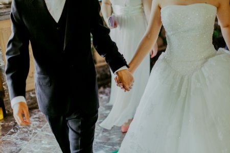 Woman Wearing White Wedding Gown Holding Hands With Man While Walking photo