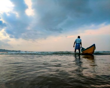 Man On Body Of Water Beside Yellow And Blue Boat photo