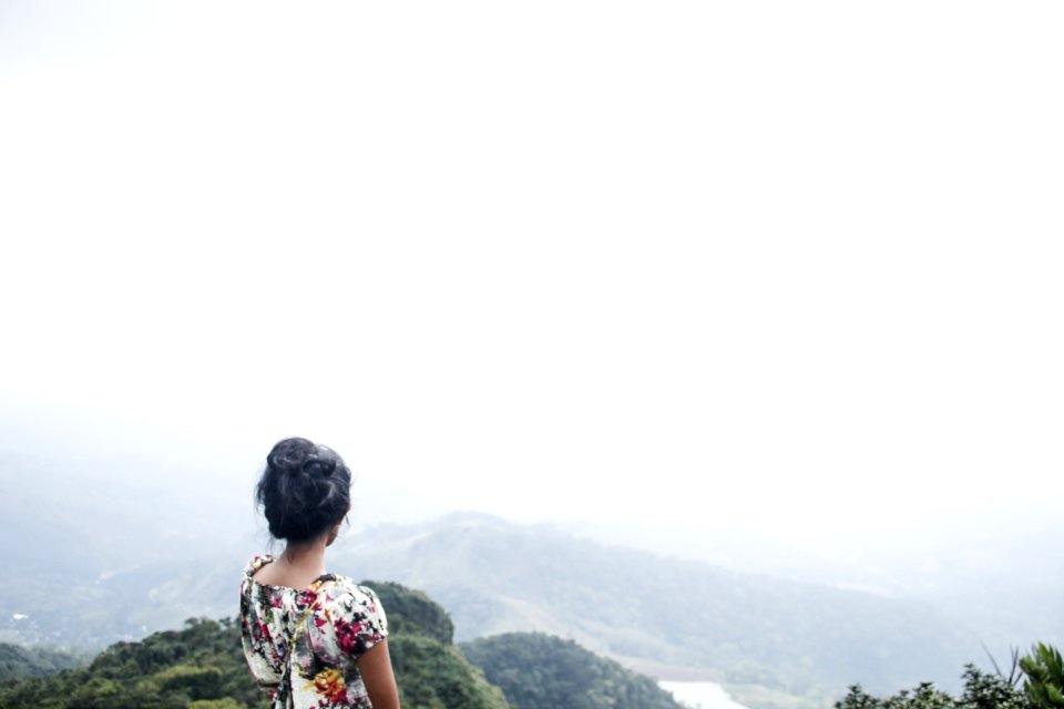 Woman Wearing Multicolored Floral Top Standing Near Mountain Under White Sky