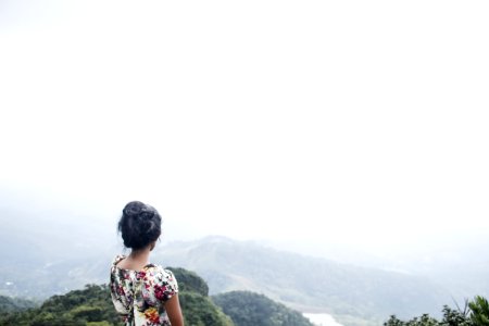 Woman Wearing Multicolored Floral Top Standing Near Mountain Under White Sky photo
