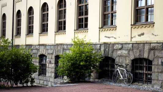 White Bicycle Parked Beside Gray Building photo