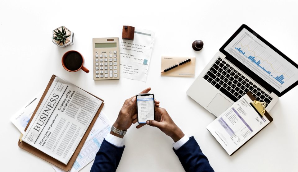 Top View Of Man Holding Android Smartphone Near Macbook And Newspaper photo