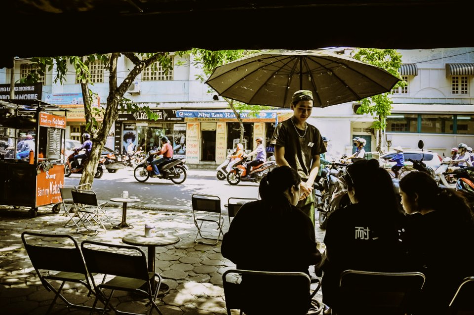 Man Standing Beside Umbrella Facing Three Women Sitting On Chairs