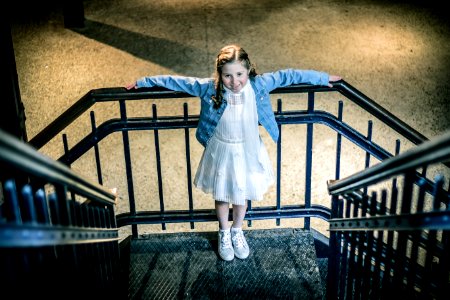 Girl Wearing Blue Jacket And White Dress Standing On Railings During Night Time photo