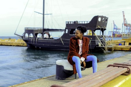 Woman In Red Cardigan Sitting On Black Metal Near Boats photo