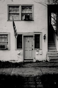 Grayscale Photo Of Concrete House With Usa Flag photo