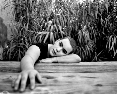Grayscale Photo Of A Person Leaning On Wooden Surface photo