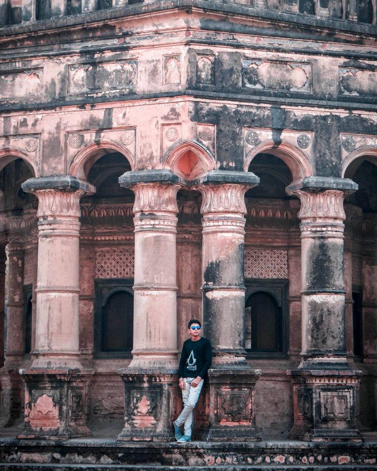 Man In Black Long-sleeved Shirt And White Denim Jeans Outfit Leaning On Concrete Building At Daytime