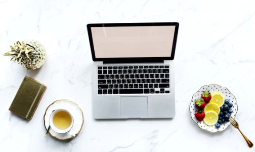 Macbook Pro Beside White Ceramic Mug And Saucer photo