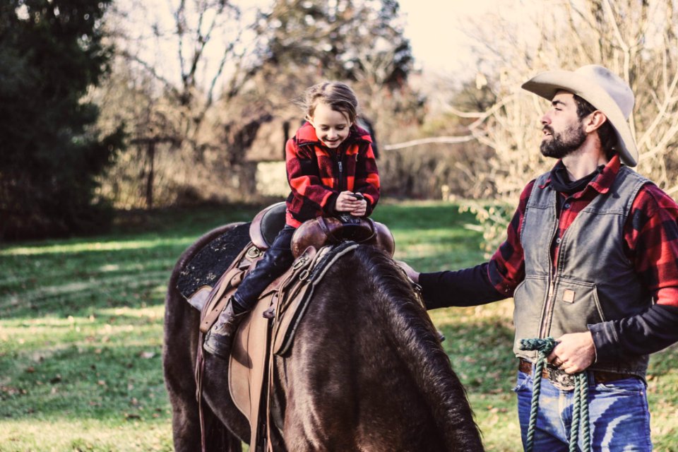 Little Girl Riding Horse Beside Man