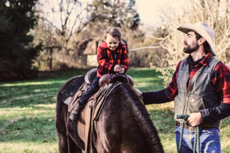 Little Girl Riding Horse Beside Man