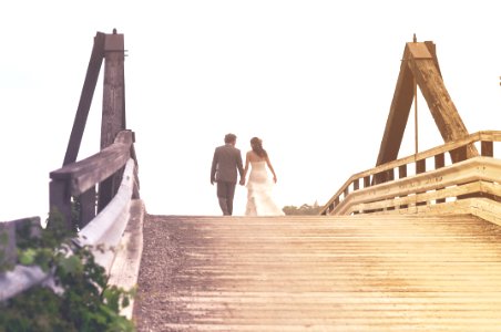 Man And Woman Holding Hands While Walking On Bridge photo