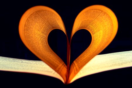 Two Lighted Pages Of Book Formed Into Heart Shape Inside A Dark Room