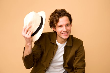 Man Wearing Brown Dress Shirt Holding White Fedora Hat photo