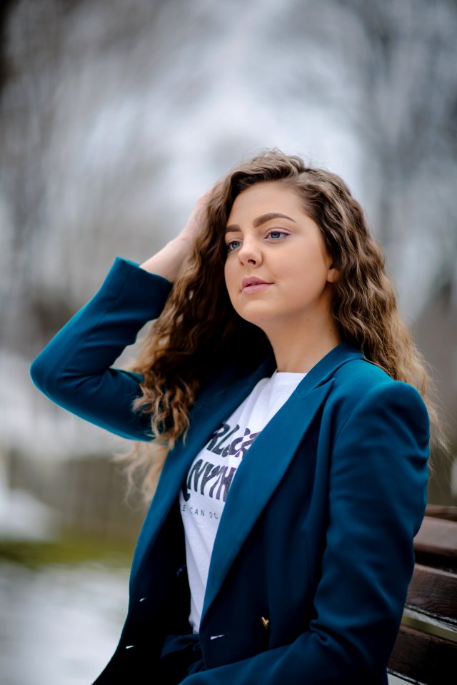 Woman Wearing Green Peak Lapel Suit Jacket Sitting On Bench