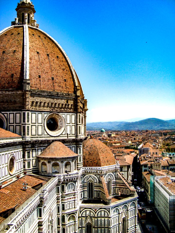 Brown And White Painted Cathedral Roof Overlooking City And Mountain Under Blue Sky photo