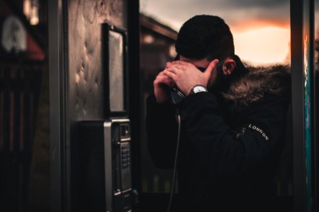 Man Wearing Black Parka Jacket Holding Telephone photo