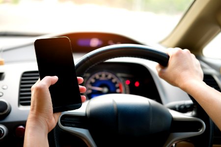 Person Holding Black Smartphone And Vehicle Steering Wheel photo