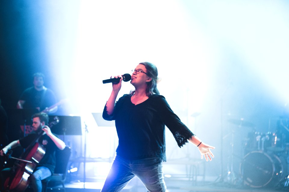 Woman Holding Microphone While Singing On Stage