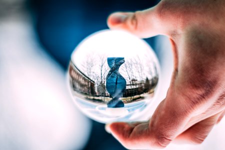 Person Holding Sphere Reflecting Dna-shaped Statue