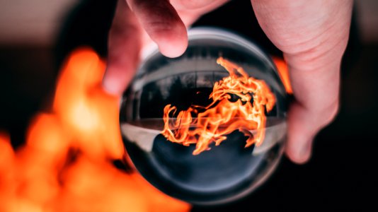 Person Holding Clear Glass Ball With Flame