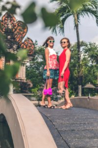 Two Women Wearing Sunglasses And Holding Bags Standing On Foot Bridge