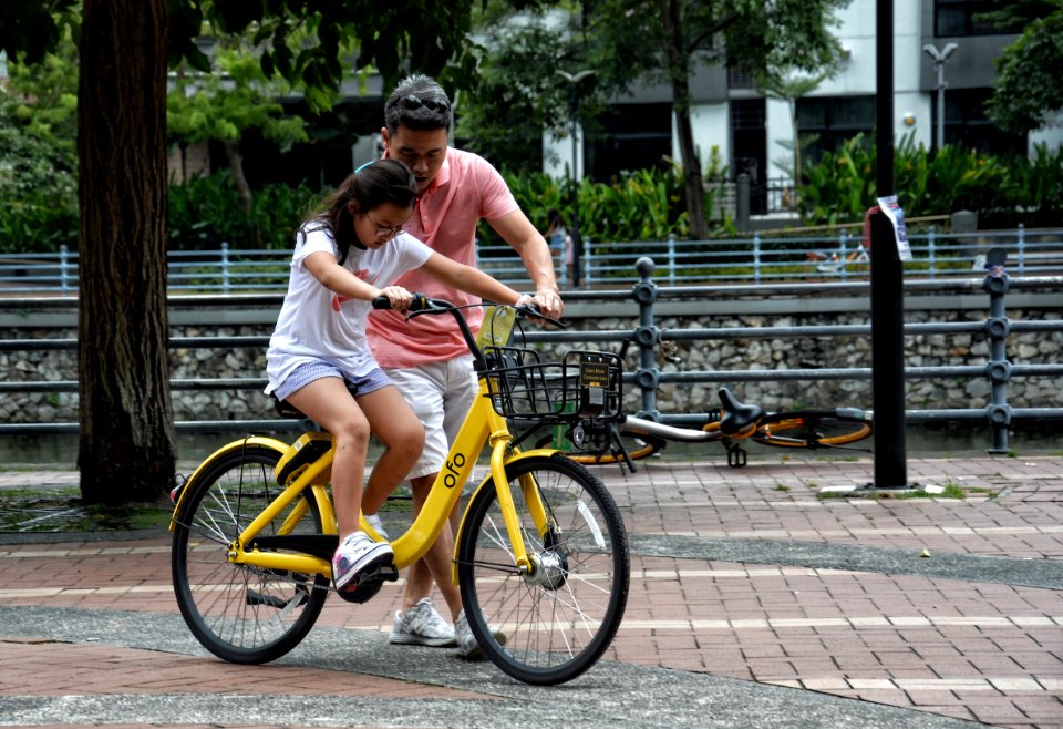 Photography Of Girl Riding Bike Beside Man