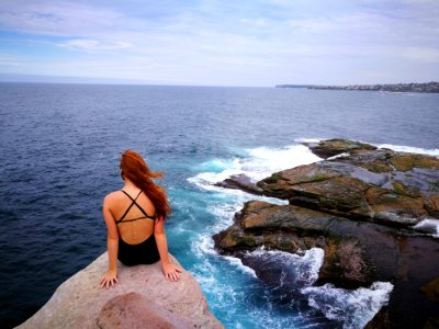 Woman Wearing Monokini On Rock Cliff Near Body Of Water