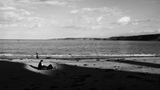 Grayscale Photo Of A Man On Sand Near The Sea photo