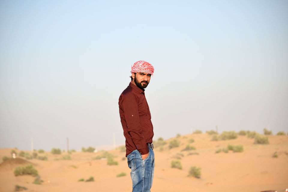 Man In Brown Collared Dress Shirt And Blue Jeans Standing In The Middle Of Brown Field